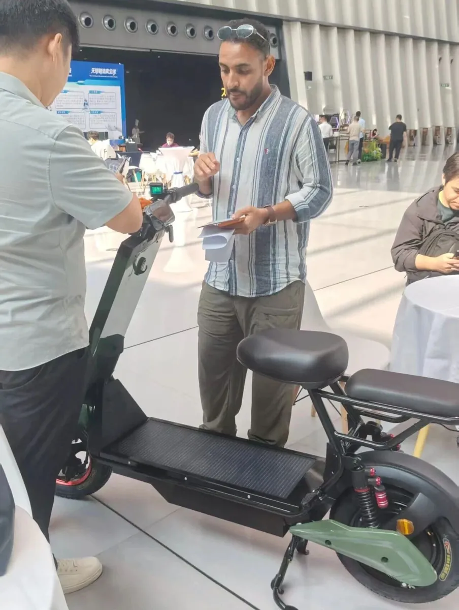 Close-up consultation on the Laineng solar e-scooter with solar panel deck at the matchmaking event